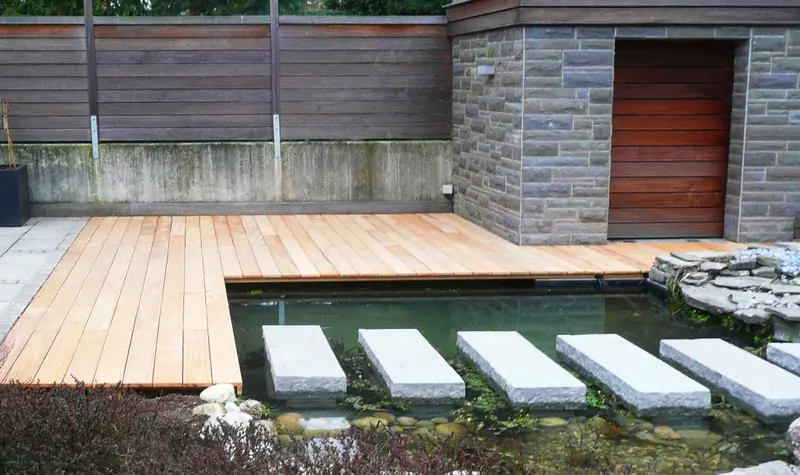 Terrassenboden aus hellem Holz mit angrenzendem Wasserbecken und Trittsteinen